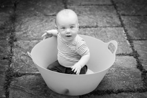 Baby boy playing in a clothes basket